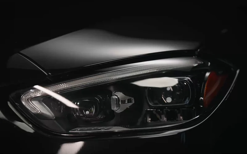 Studio light tracing the headlamp and sculpted black paint of a Mercedes