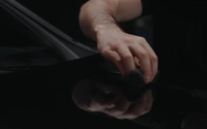 An applicator moving carefully across black vehicle paint