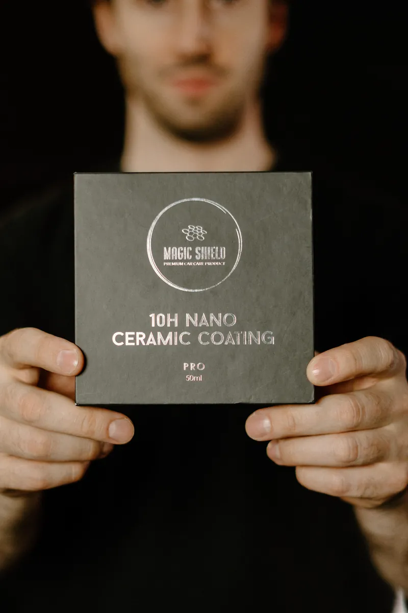 A person holding a Magic Shield Ceramic Coating PRO 10H box.
